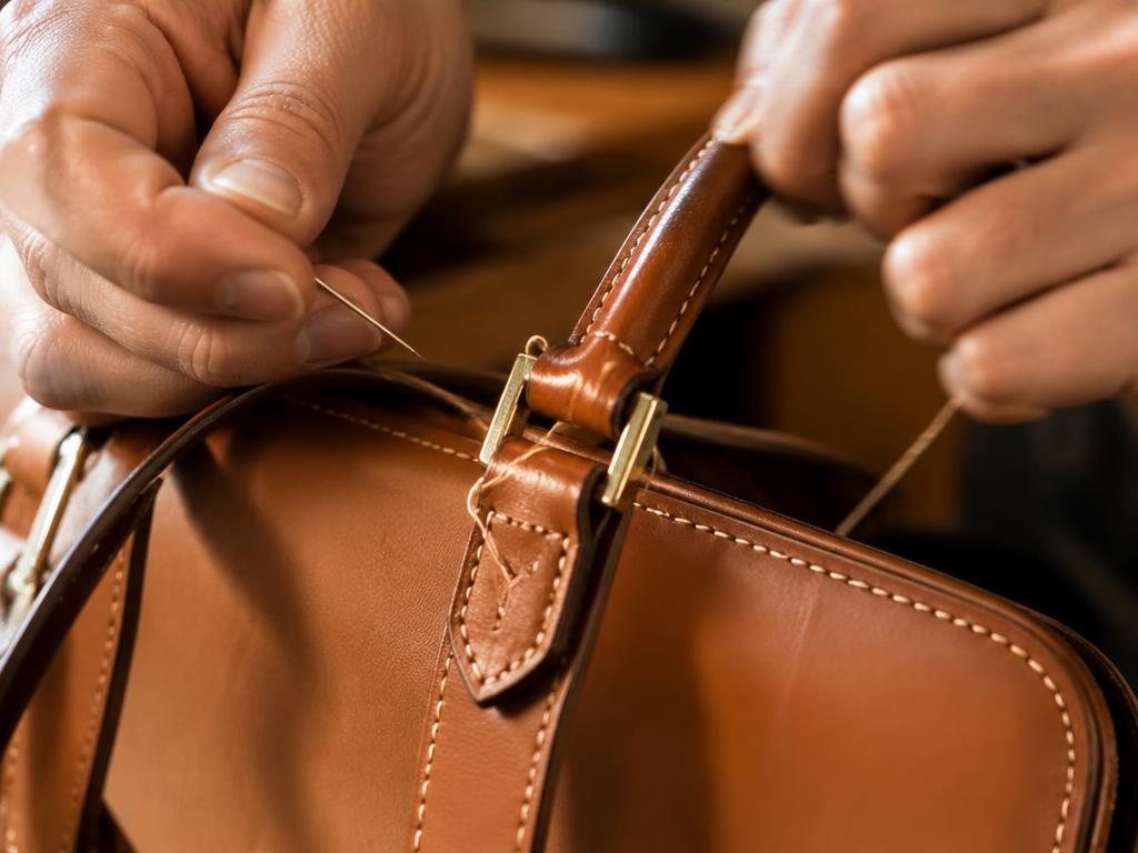 Hand-stitching a leather handbag handle with needle and thread
